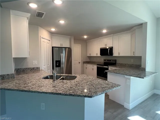 Kitchen featuring a sink, visible vents, appliances with stainless steel finishes, and a peninsula