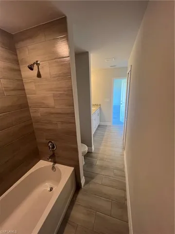 Bathroom featuring visible vents, baseboards, toilet, vanity, and  shower combination