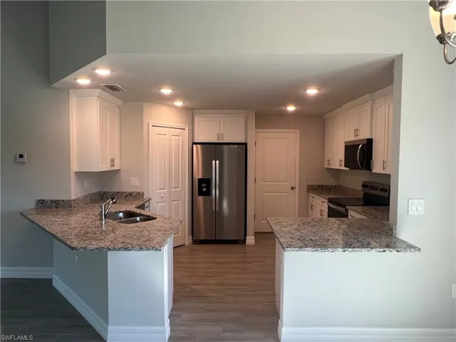 Kitchen with a peninsula, visible vents, appliances with stainless steel finishes, and a sink