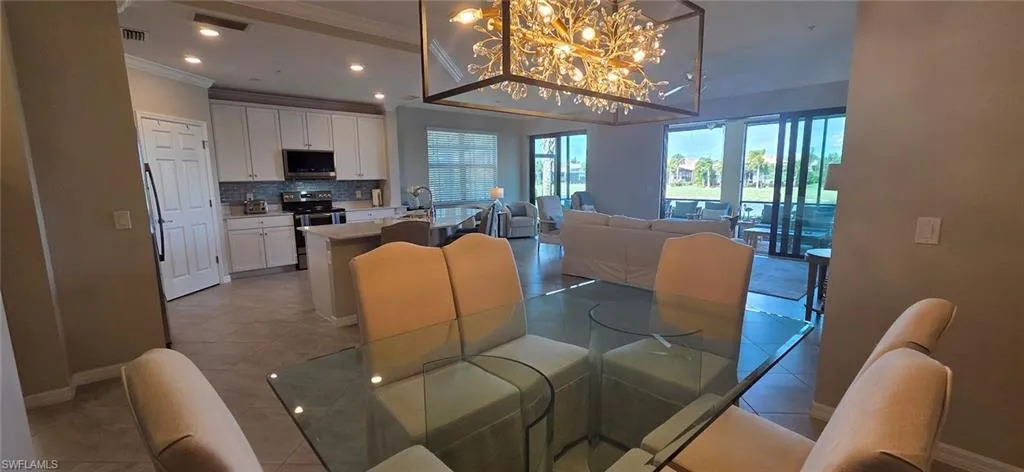 Dining room with suspended lighting, light tile patterned flooring, and crown molding