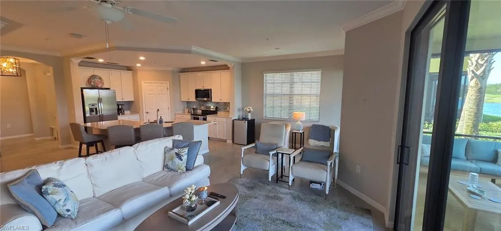 Living room with ceiling fan, crown molding, arched walkways, and light tile patterned floors