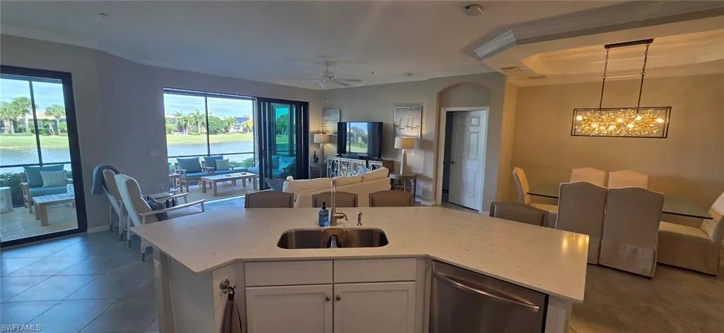 Kitchen featuring white cabinets, light stone counters, open floor plan, dishwasher, and a kitchen island with sink