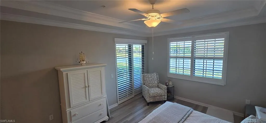 Bedroom featuring dark wood-style flooring, ceiling fan, crown molding, and access to outside