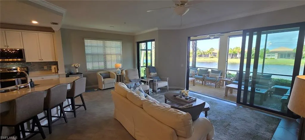 Living room featuring crown molding, ceiling fan, a water view, dark tile patterned flooring, and recessed lighting