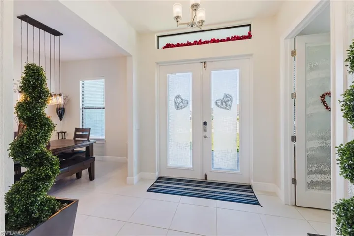 Entrance foyer featuring french doors, a chandelier, and light tile patterned floors