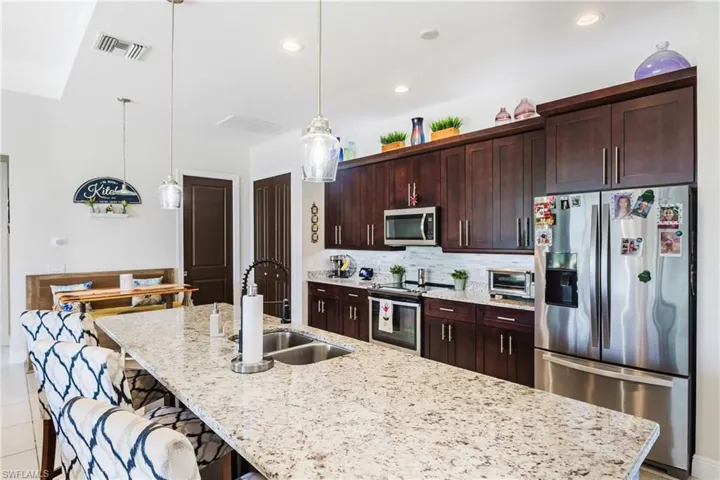 Kitchen with appliances with stainless steel finishes, light stone countertops, a spacious island, and recessed lighting