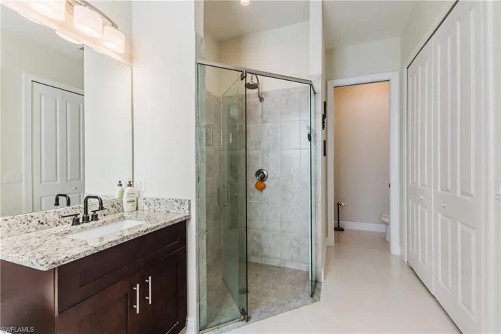 Bathroom featuring a closet, a shower stall, vanity, and light tile patterned flooring