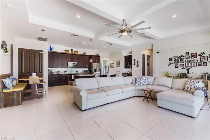 Living area with recessed lighting, light tile patterned flooring, ceiling fan, beamed ceiling, and coffered ceiling