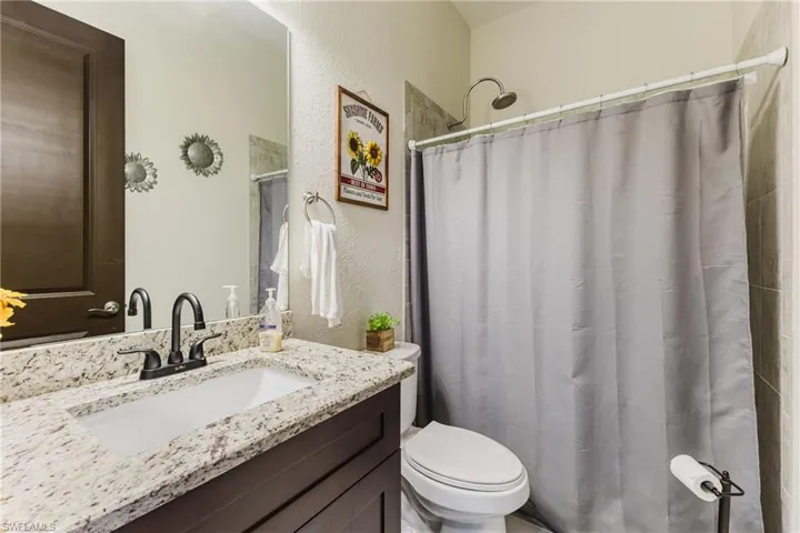 Bathroom featuring a textured wall, a shower with curtain, and vanity