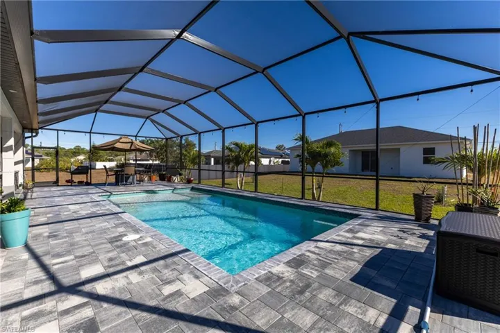 Swimming pool with a lawn, a sunroom, glass enclosure, and a patio