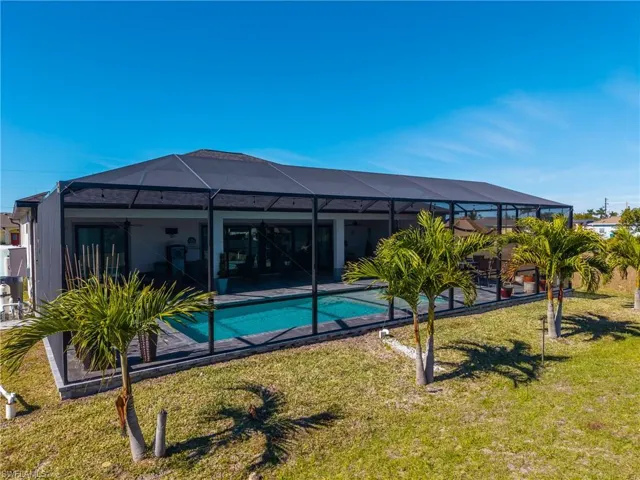 Rear view of house featuring a sunroom, glass enclosure, a yard, a patio, and an outdoor pool