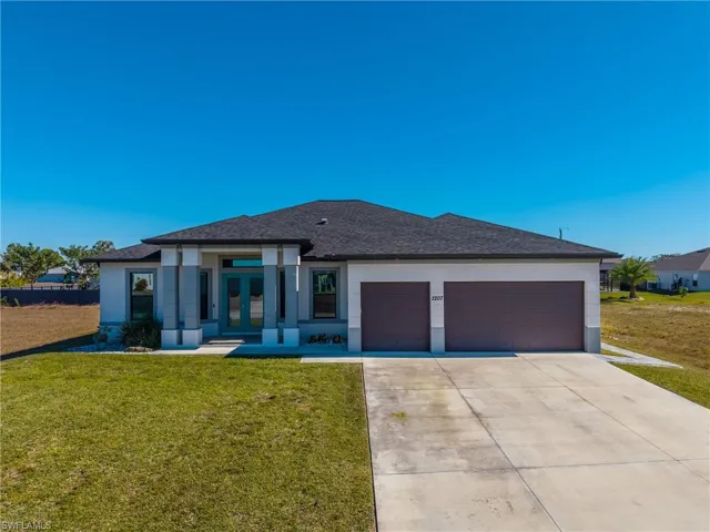 View of front of house with french doors, stucco siding, driveway, and a garage