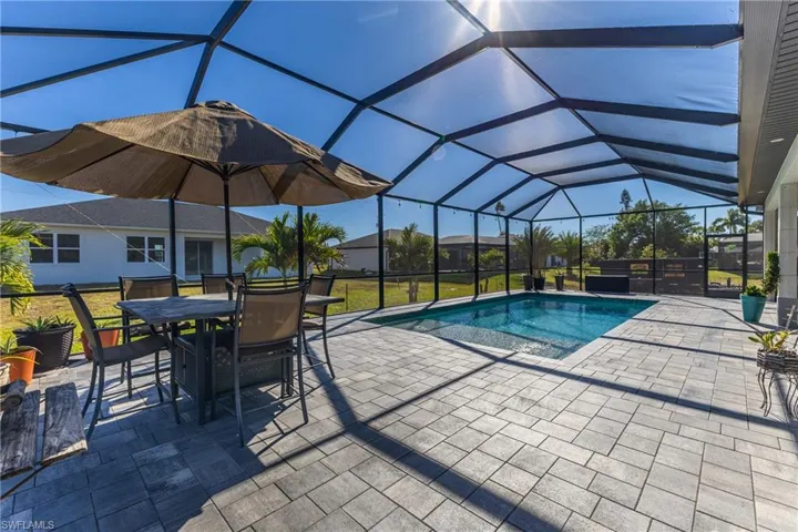 Outdoor pool featuring a sunroom, a patio, glass enclosure, and outdoor dining space
