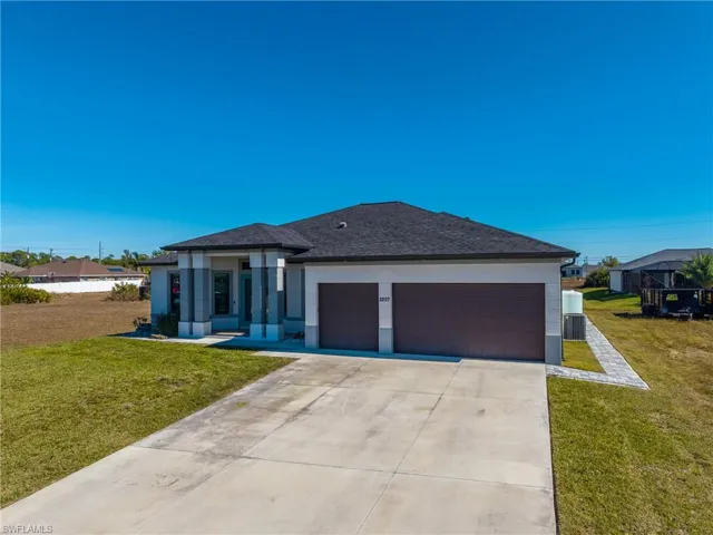 Prairie-style home featuring a front yard, stucco siding, concrete driveway, and a shingled roof