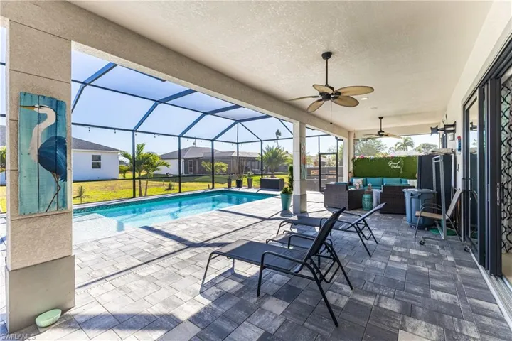 Swimming pool featuring a patio, an outdoor hangout area, a sunroom, glass enclosure, and a yard