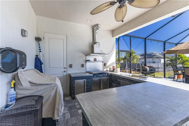 View of patio / terrace with a lanai, a sunroom, an outdoor kitchen, a ceiling fan, and outdoor dining space