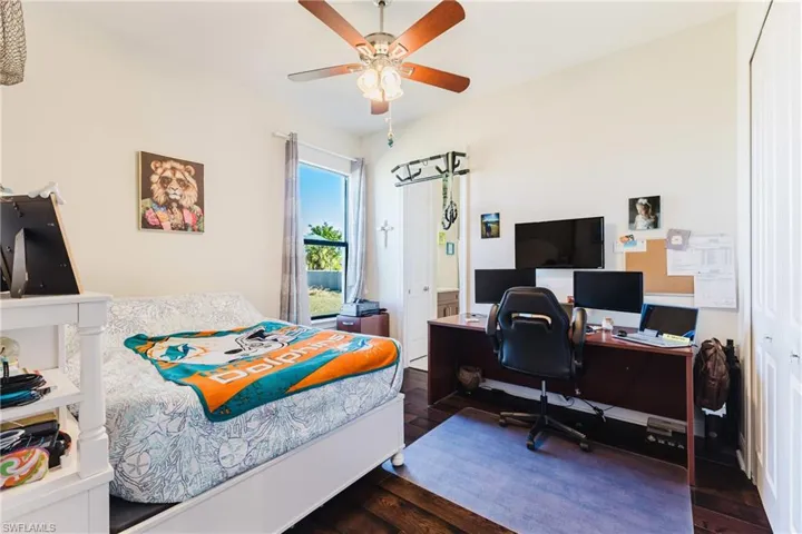 Bedroom featuring dark wood-style floors, a ceiling fan, a closet, and a desk