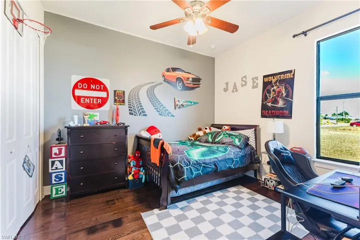 Bedroom featuring dark wood-style floors, a ceiling fan, and a desk