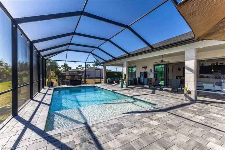 Swimming pool featuring an outdoor hangout area, a patio area, a sunroom, and glass enclosure