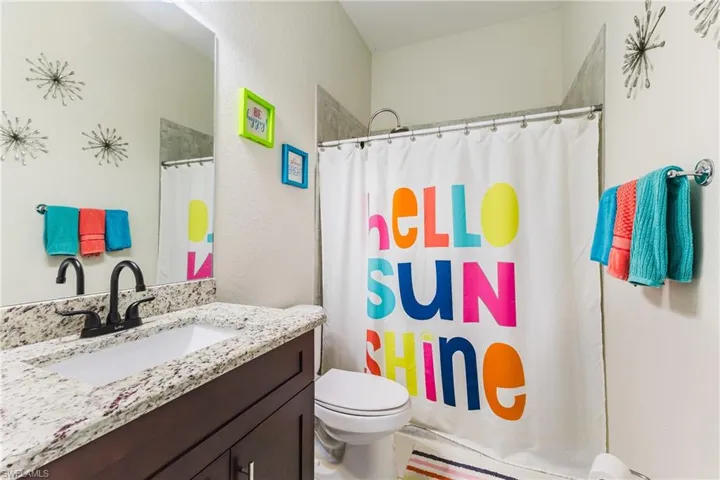 Bathroom with vanity, a shower with shower curtain, and a textured wall
