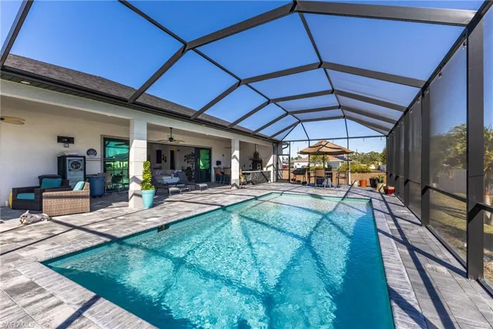 Swimming pool with a sunroom, glass enclosure, outdoor dining area, a patio area, and an outdoor living space