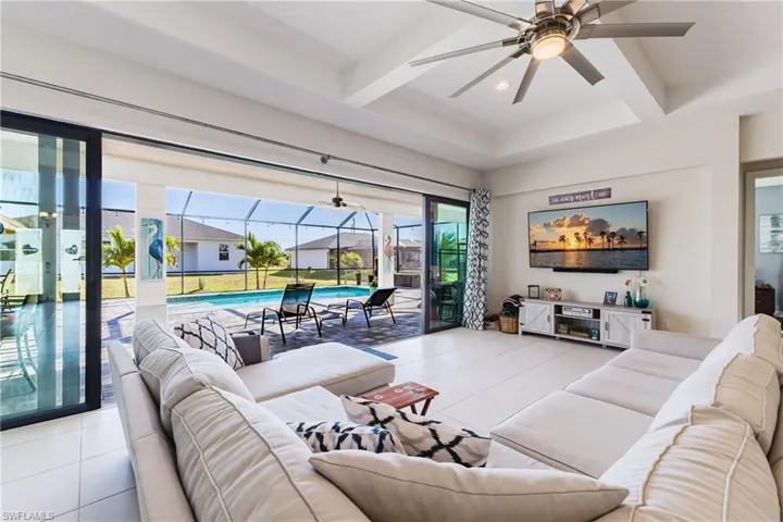 Tiled living room with a sunroom, a ceiling fan, coffered ceiling, beamed ceiling, and recessed lighting
