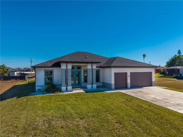 Prairie-style home with french doors, a front lawn, driveway, stucco siding, and a garage