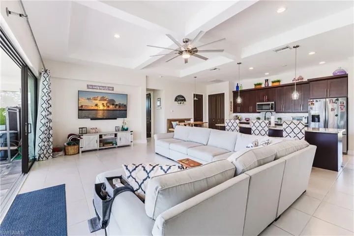 Living room with a ceiling fan, coffered ceiling, recessed lighting, and beamed ceiling