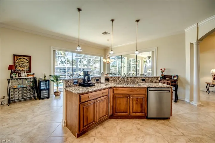 Kitchen with wood finish cabinets, stainless steel dishwasher, light stone countertops, ornamental molding, and beverage cooler