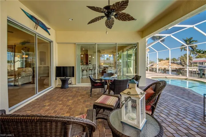 View of patio / terrace featuring a lanai, a ceiling fan, a sunroom, outdoor dining space, and an outdoor pool