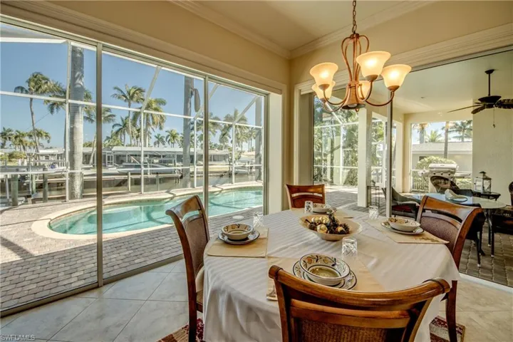 Tiled dining space with hanging lights, a water view, crown molding, and a ceiling fan
