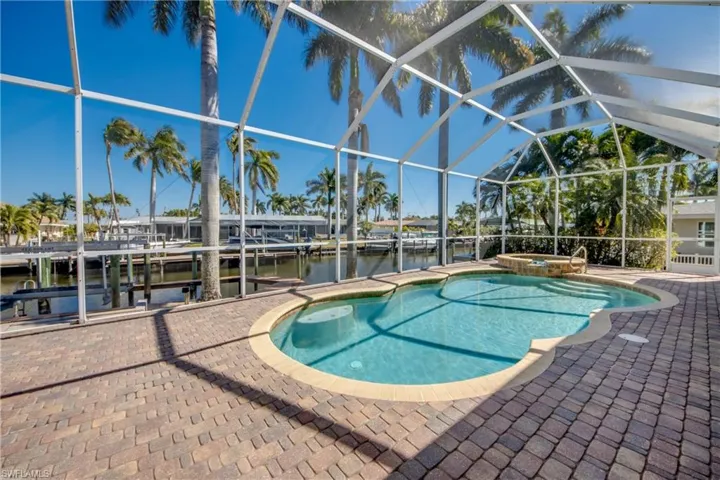 Relaxing pool / spa with a lanai, a dock, and a water view