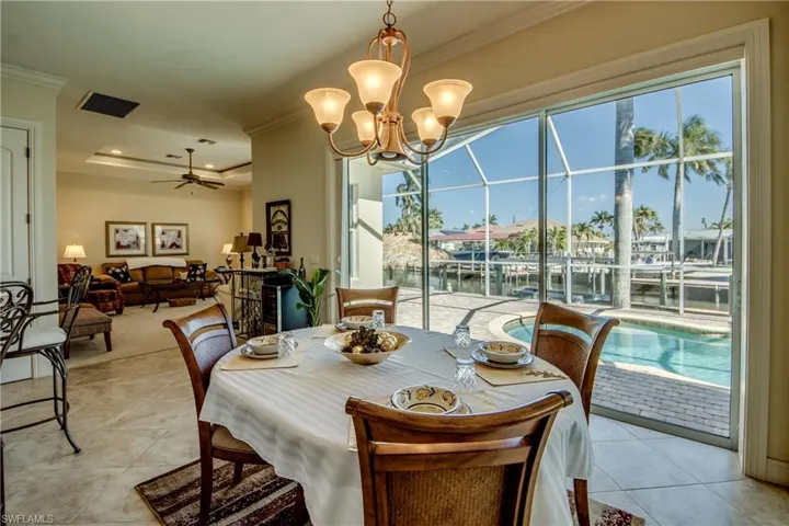 Dining room with ceiling fan, a chandelier, a tray ceiling, a water view, and crown molding