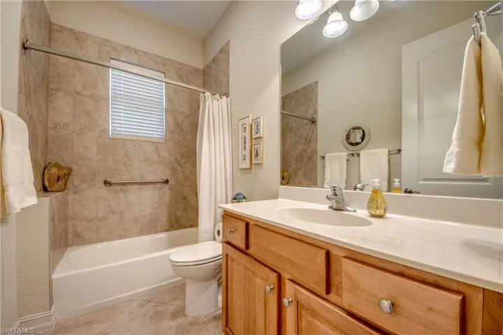 Full bath with vanity, shower / bathtub combination with curtain, and light tile patterned floors