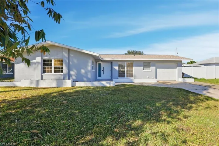 Single story home with stucco siding, a garage, and driveway