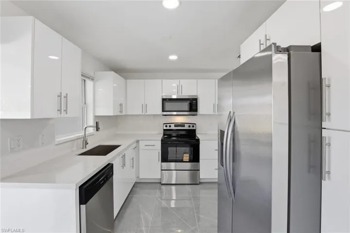 Kitchen featuring stainless steel appliances, white cabinets, recessed lighting, and light stone countertops
