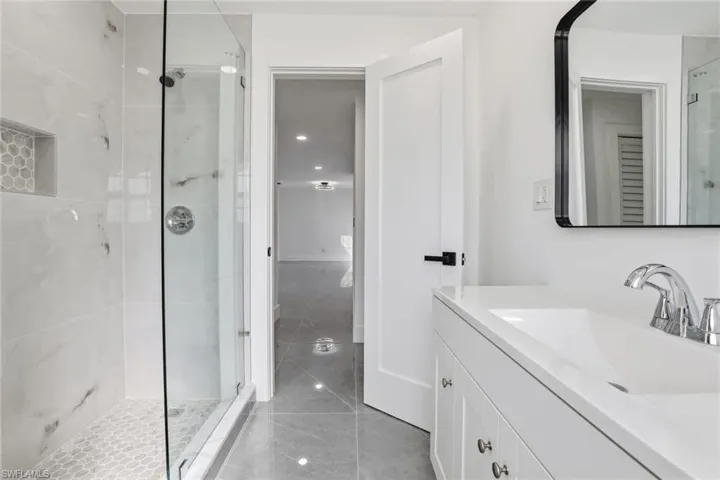 Bathroom featuring vanity, a stall shower, light tile patterned floors, and recessed lighting