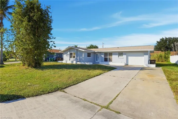Ranch-style home with driveway, a front lawn, stucco siding, and an attached garage