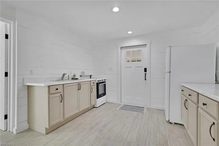 Kitchen featuring light countertops, freestanding refrigerator, recessed lighting, electric stove, and light wood-type flooring