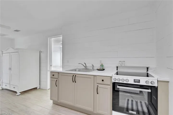 Kitchen featuring electric range oven, light wood finished floors, wooden walls, and light stone countertops