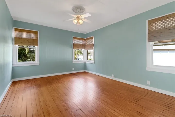 Spare room featuring ceiling fan, hardwood / wood-style floors, and a wealth of natural light