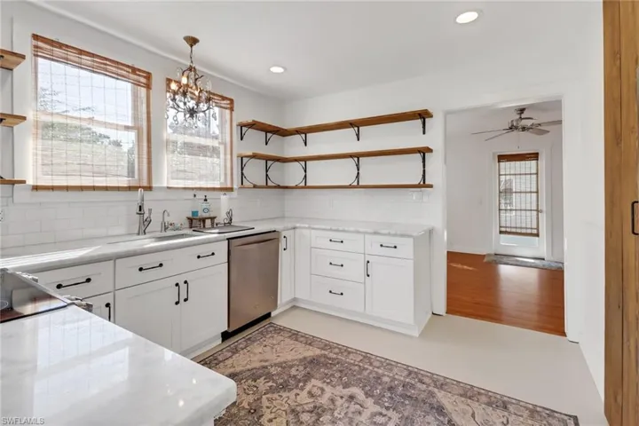 Kitchen featuring sink, hanging light fixtures, stainless steel dishwasher, a wealth of natural light, and white cabinets
