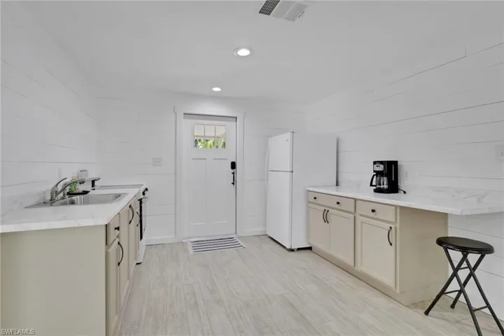 Kitchen with freestanding refrigerator, a breakfast bar, recessed lighting, and light wood-type flooring