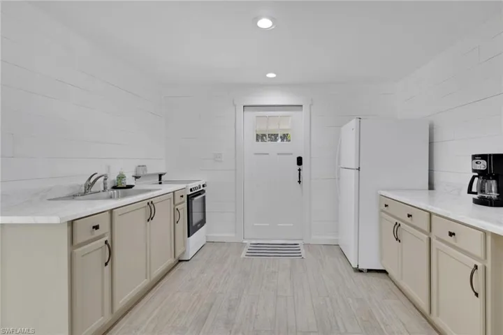 Kitchen with light countertops, freestanding refrigerator, electric range oven, recessed lighting, and light wood finished floors