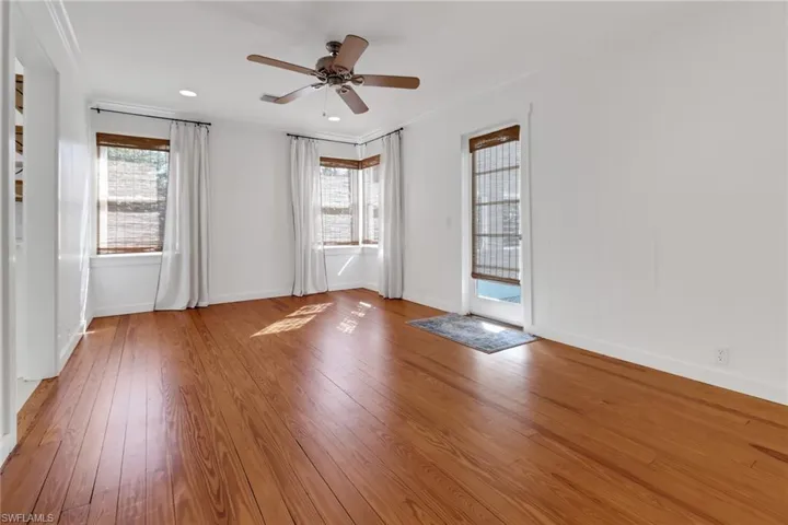 Spare room featuring a wealth of natural light, wood-type flooring, ornamental molding, and ceiling fan