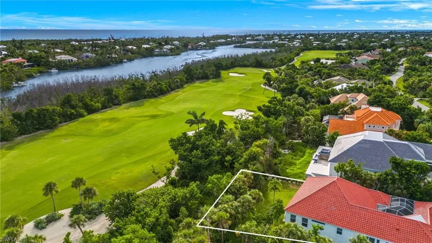 Aerial view of residential area featuring a local golf course, a nearby body of water, and property parcel outlined