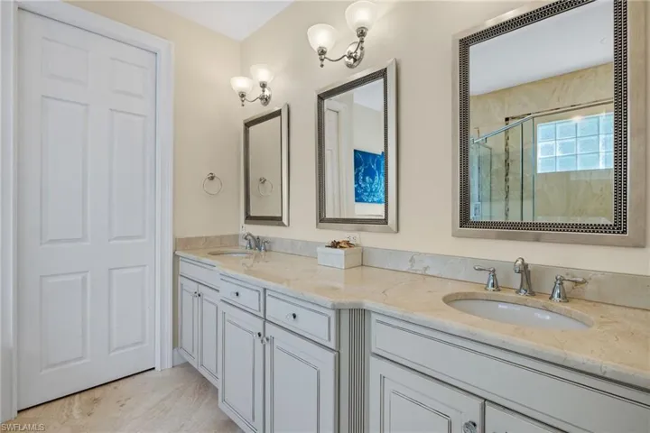 Full bath featuring double vanity and a marble finish shower