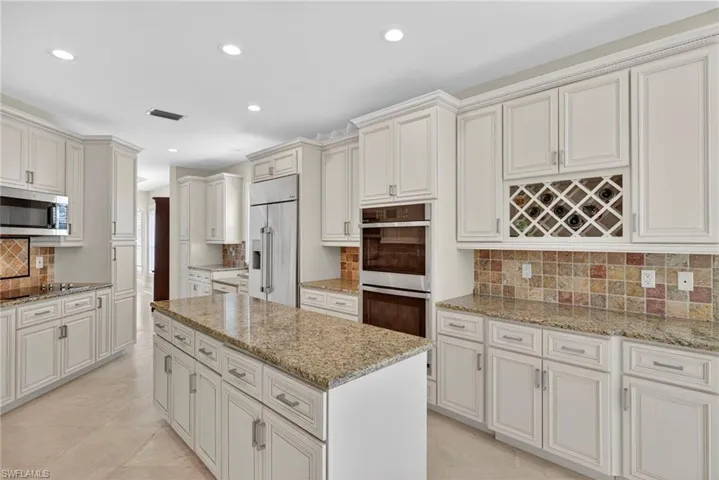 Kitchen featuring backsplash, stainless steel appliances, light stone counters, recessed lighting, and a center island