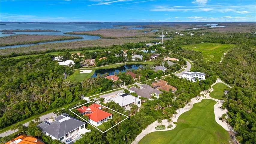 Aerial perspective of suburban area with a golf course, a large body of water, and property parcel outlined