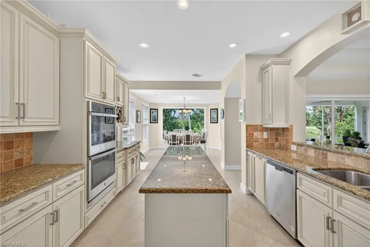 Kitchen featuring tasteful backsplash, dark stone counters, cream cabinets, recessed lighting, and stainless steel appliances